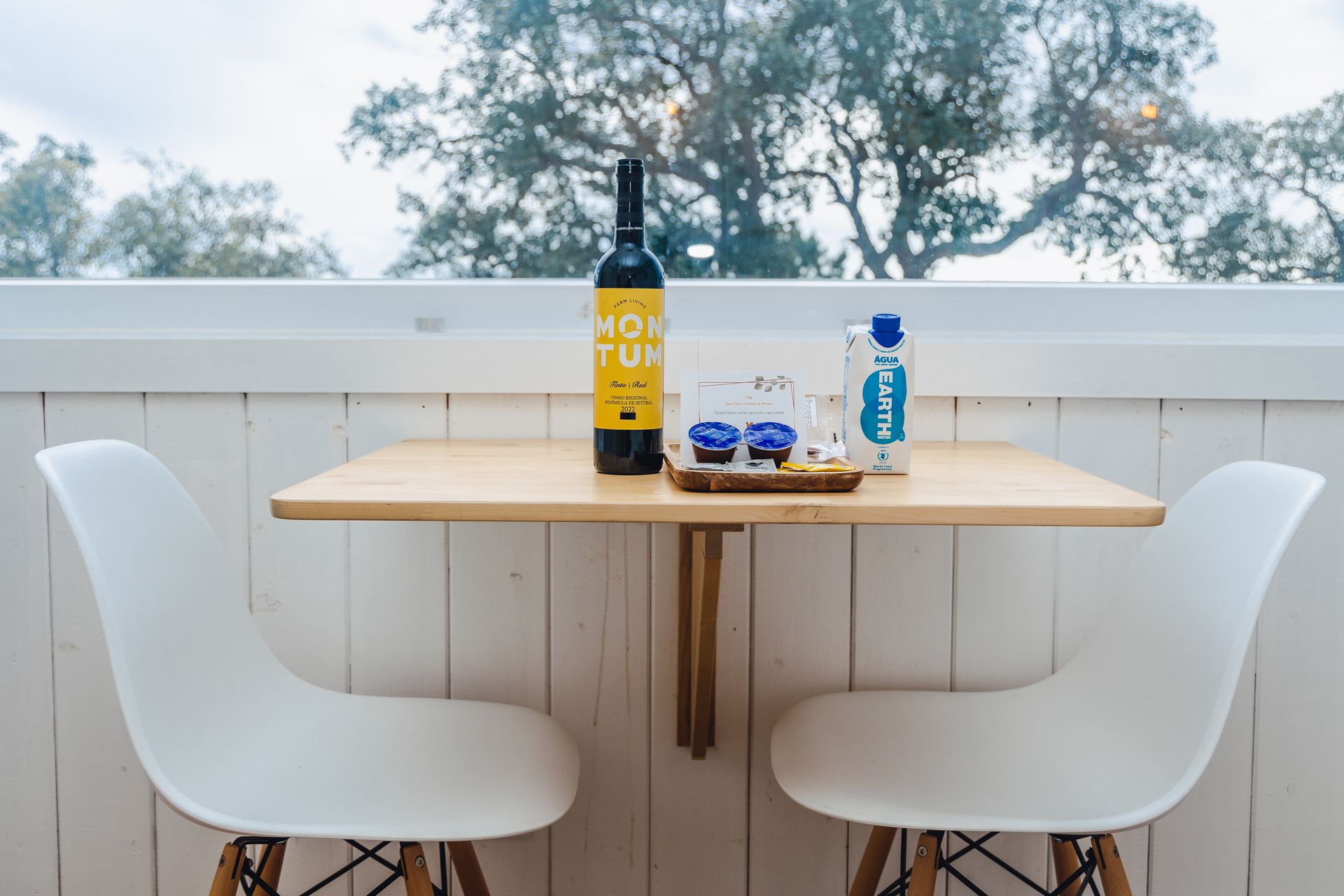 A table with two chairs and a bottle of wine on it
