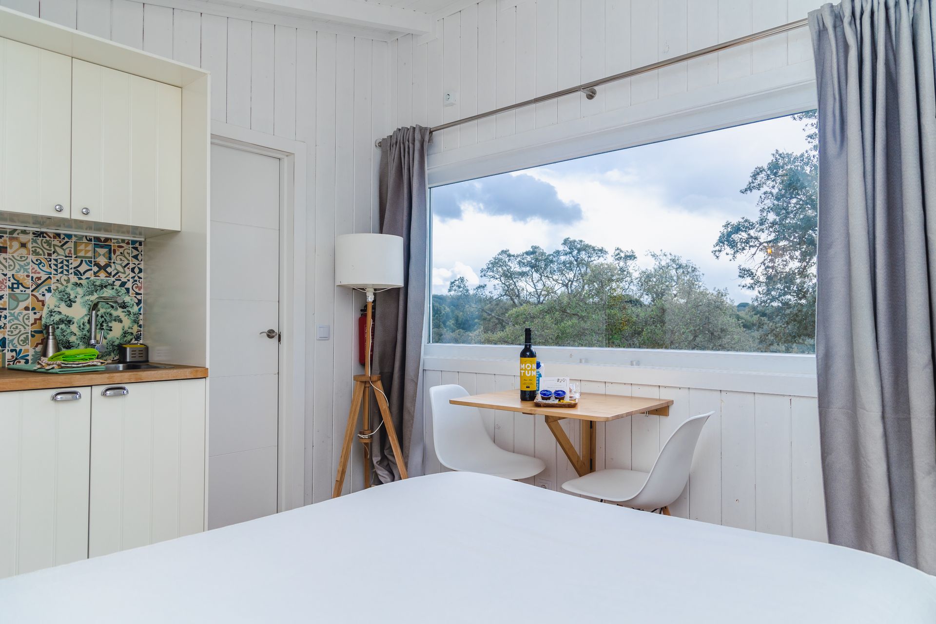 A bedroom with a table and chairs and a large window.
