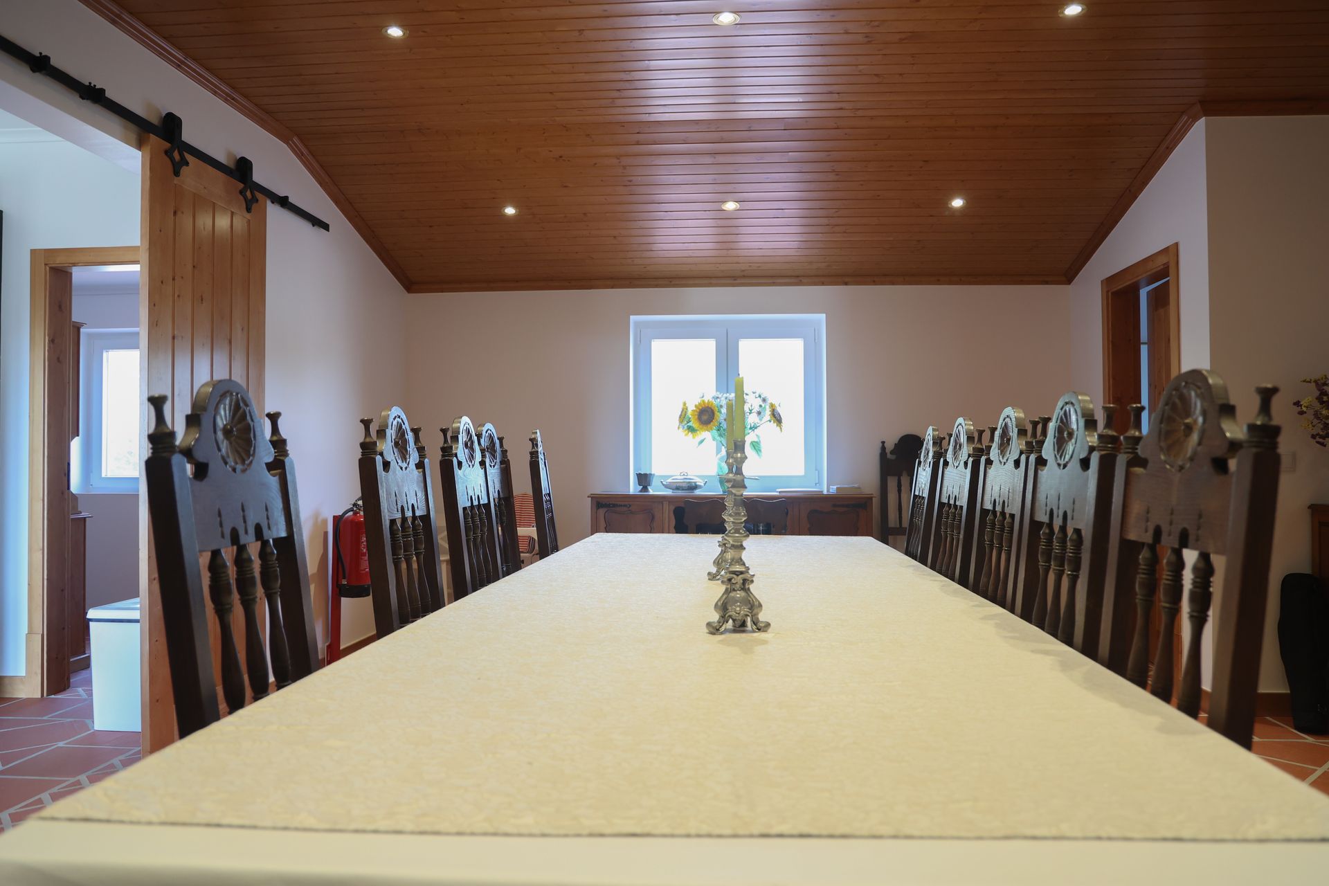 A long table with a white tablecloth and chairs in a room.