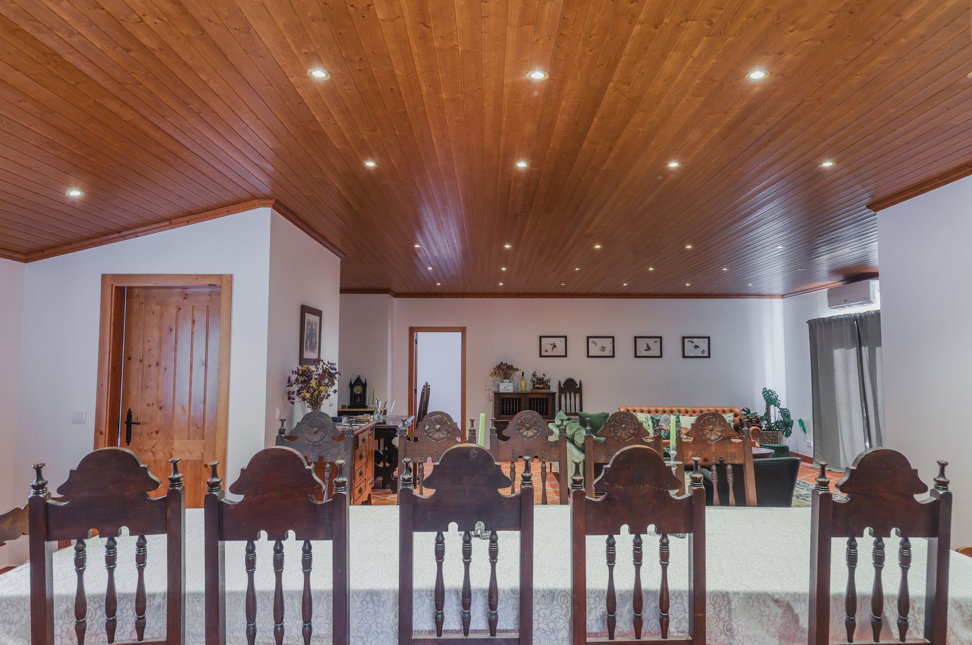 A dining room with a wooden ceiling and a table and chairs