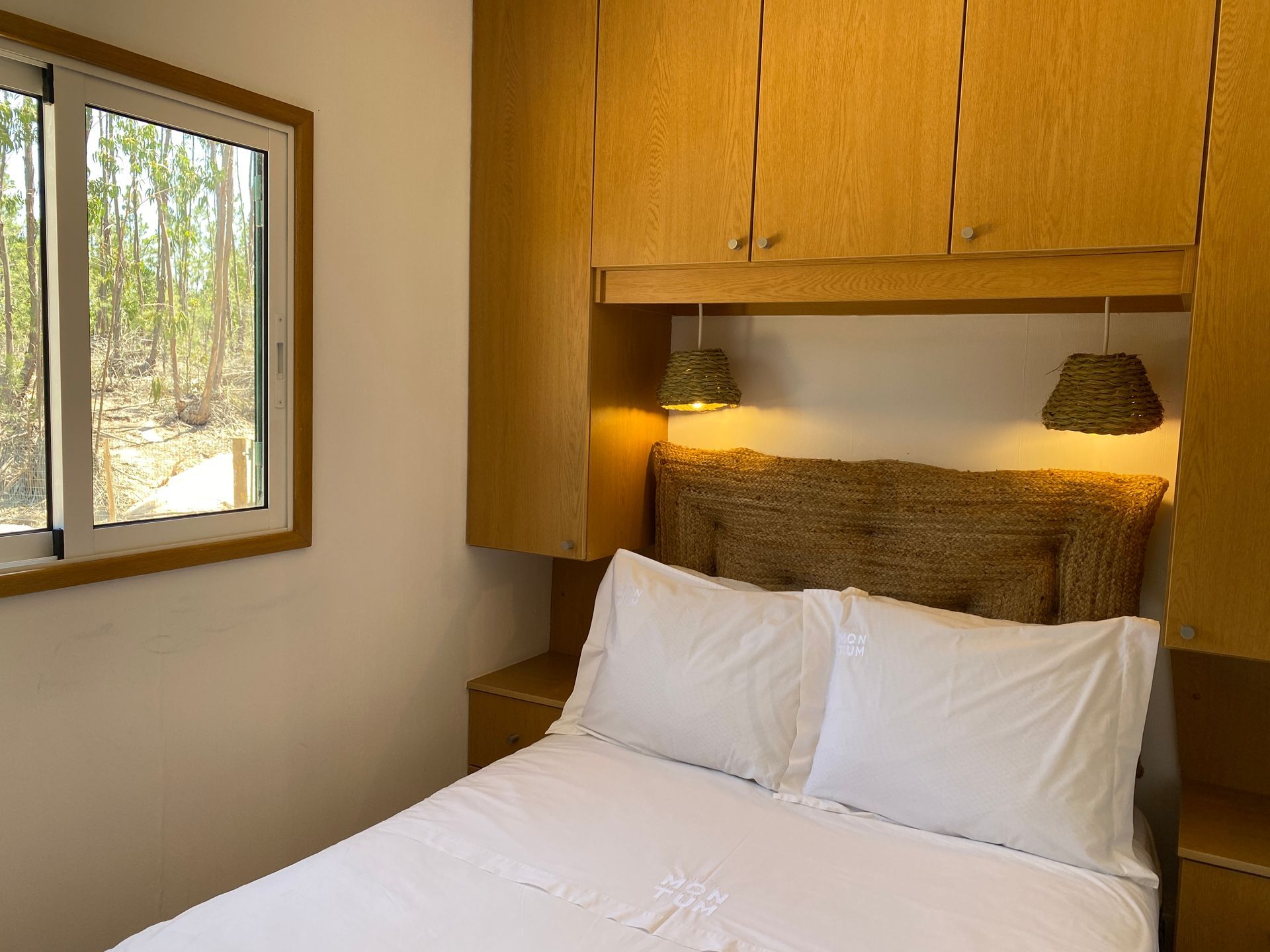 A bedroom with a bed and a window with trees in the background