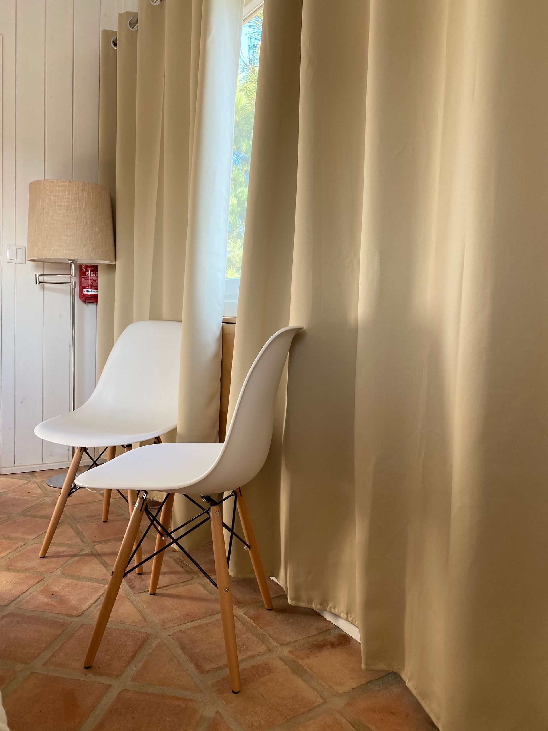 Two white chairs are sitting next to each other in a room with curtains.