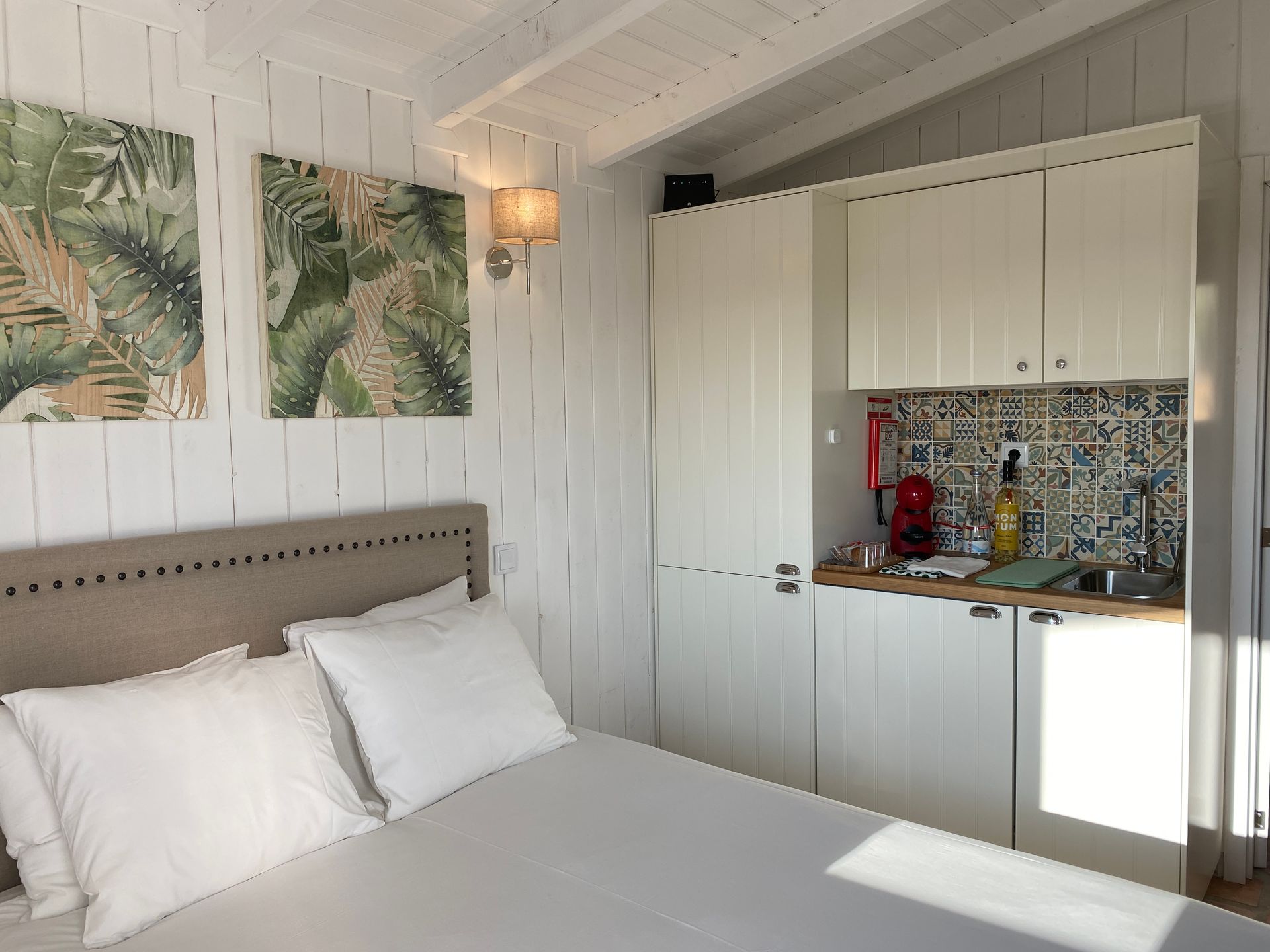 A bedroom with a bed and a kitchen in the corner.