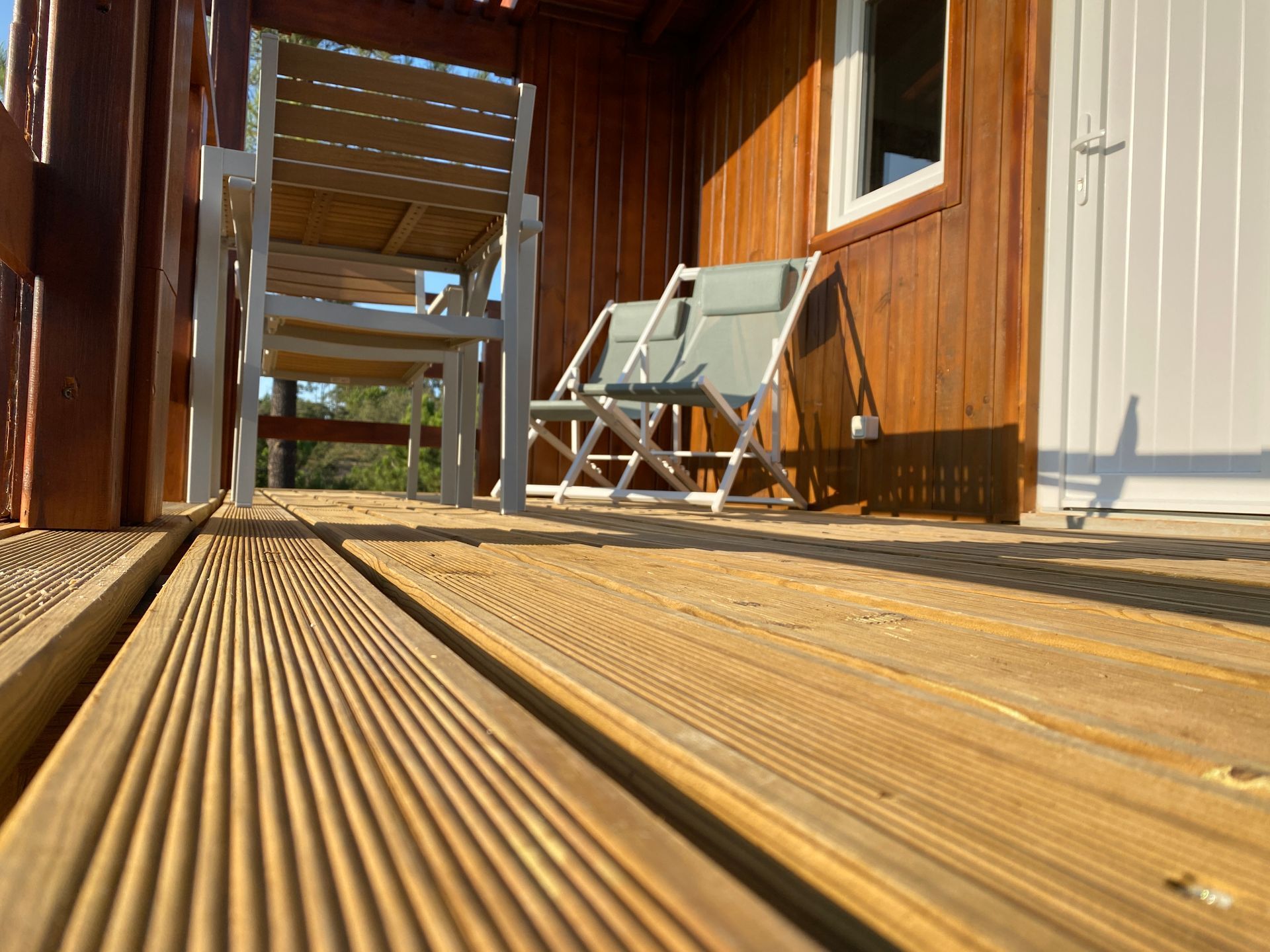 A wooden deck with chairs and ottomans in front of a wooden house.