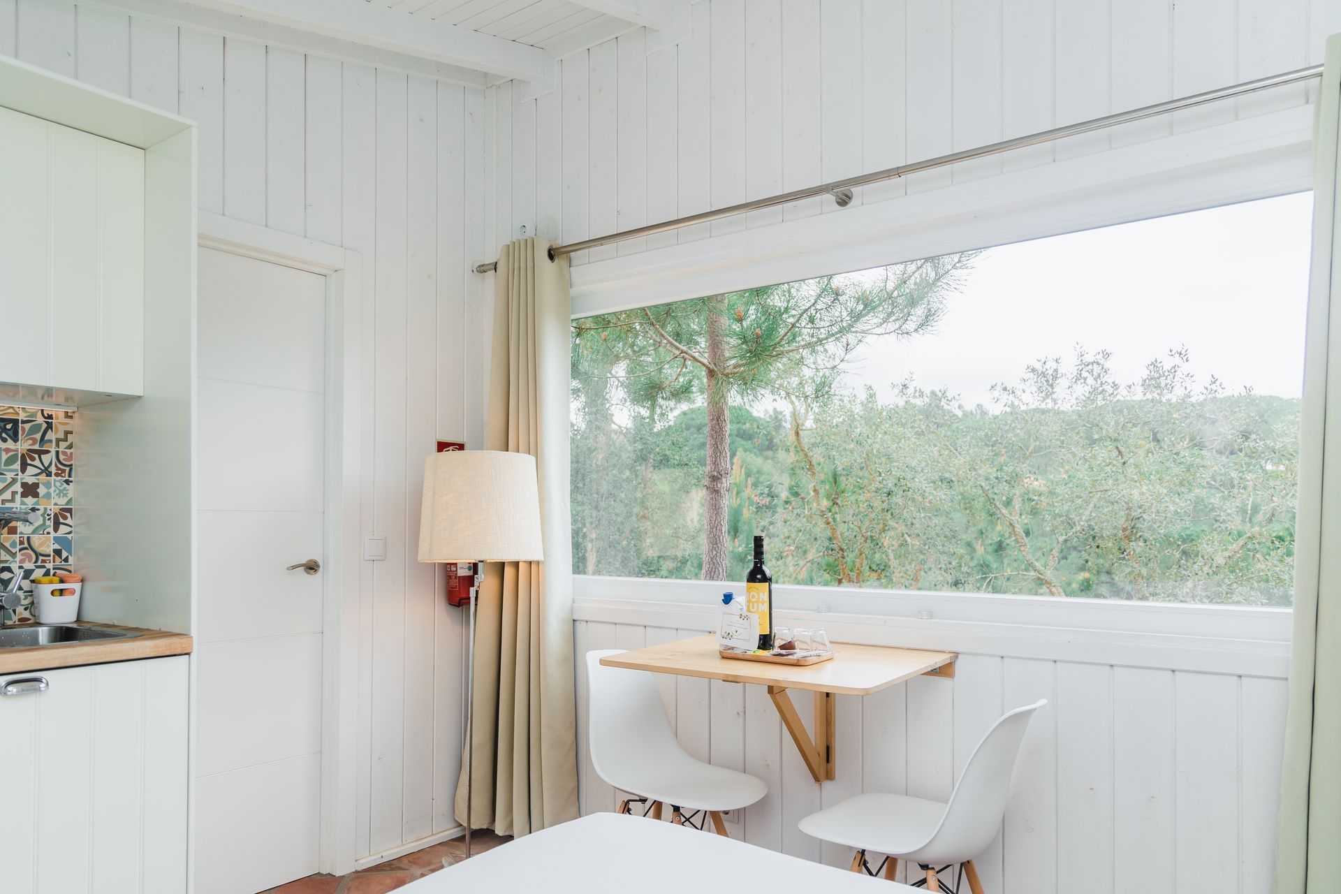 There is a table with a bottle of wine on it in the room.