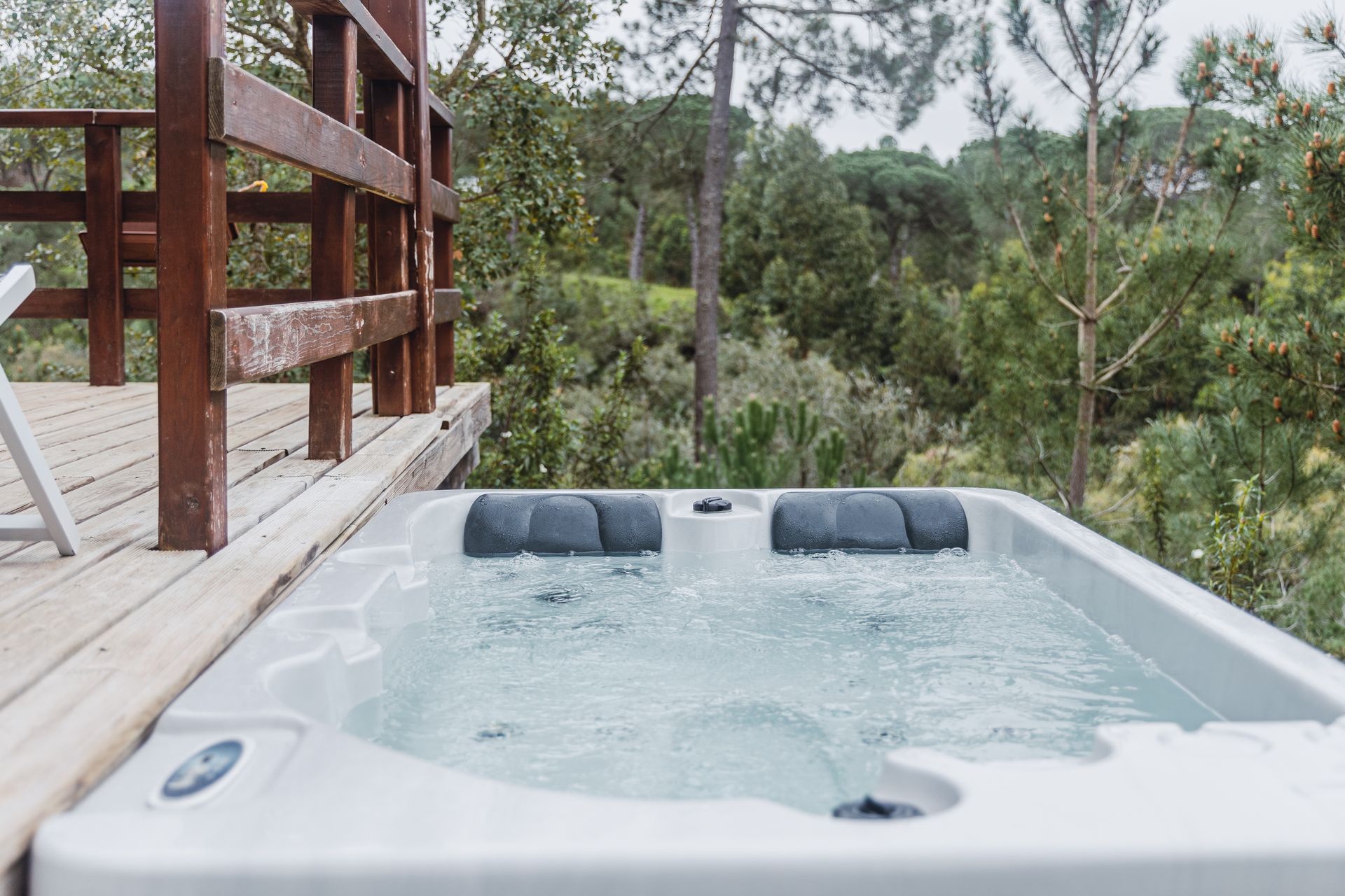 A hot tub is sitting on top of a wooden deck surrounded by trees.