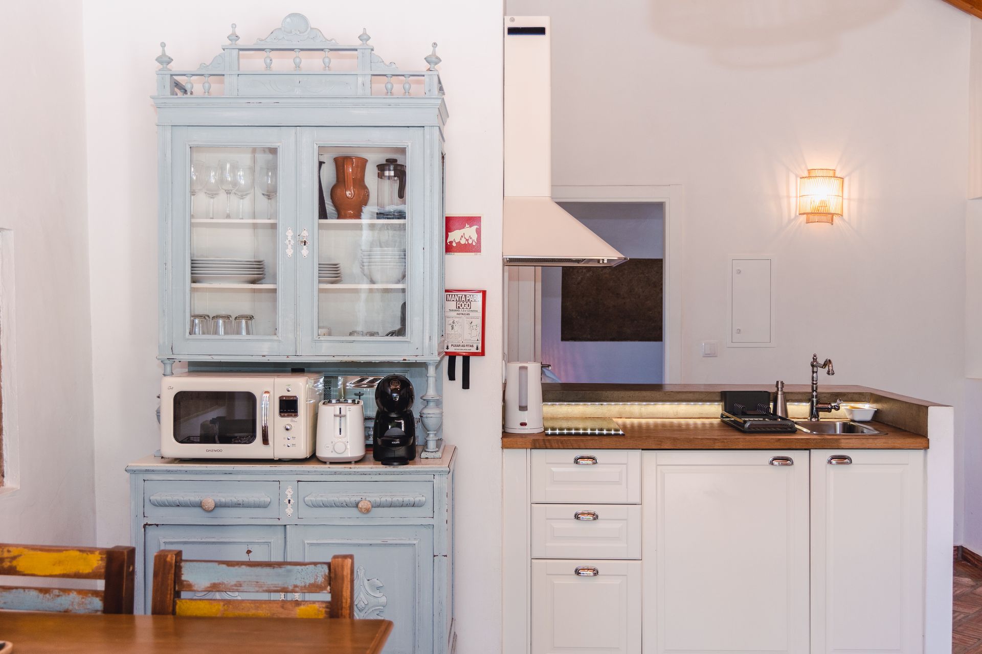 A kitchen with a blue cabinet , white cabinets , a microwave and a sink.