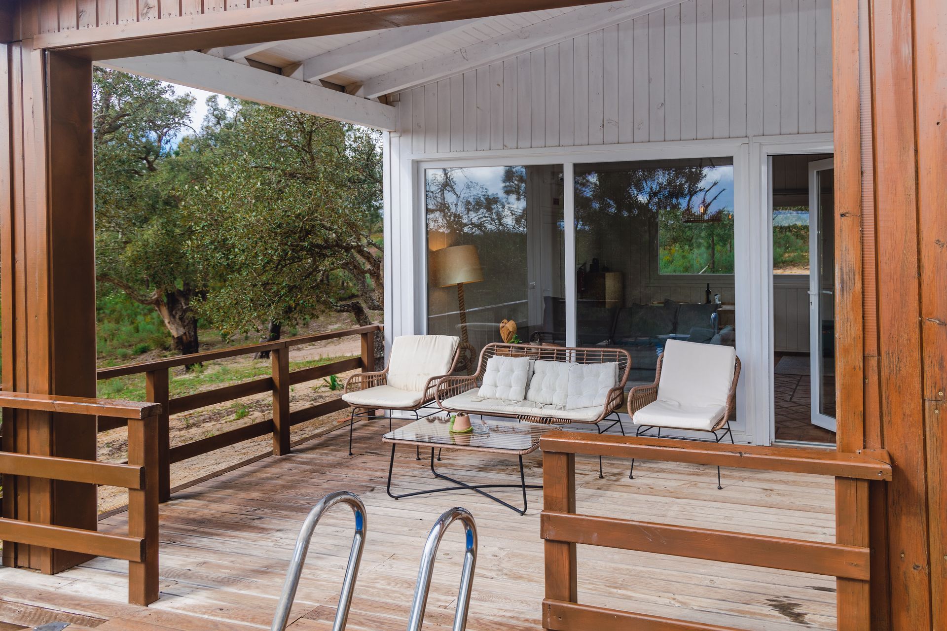 A wooden deck with chairs , a table and a swimming pool.