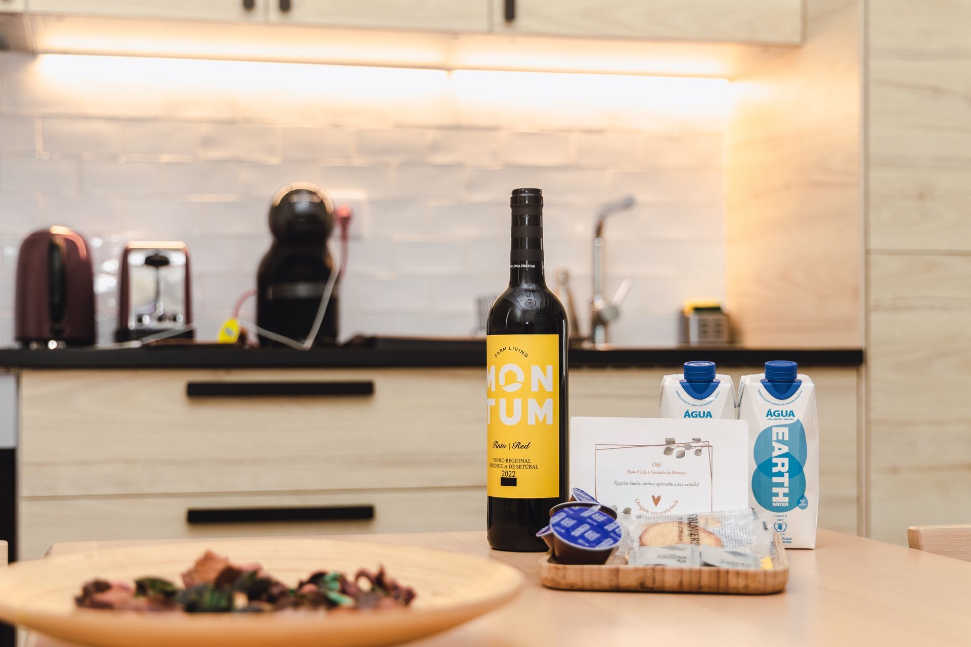 A bottle of wine is sitting on a wooden table in a kitchen.