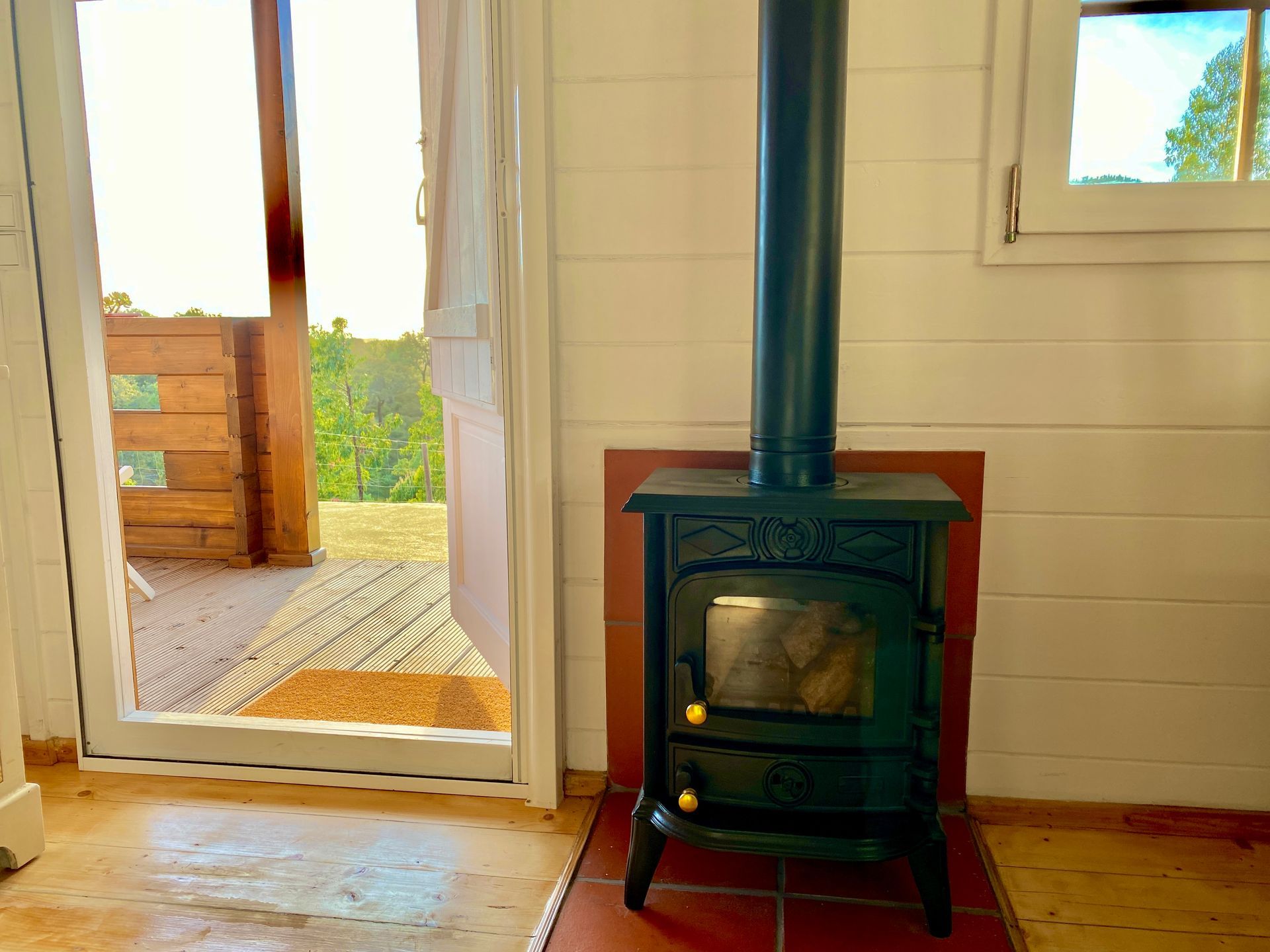 A wood stove is sitting in a room next to a window.