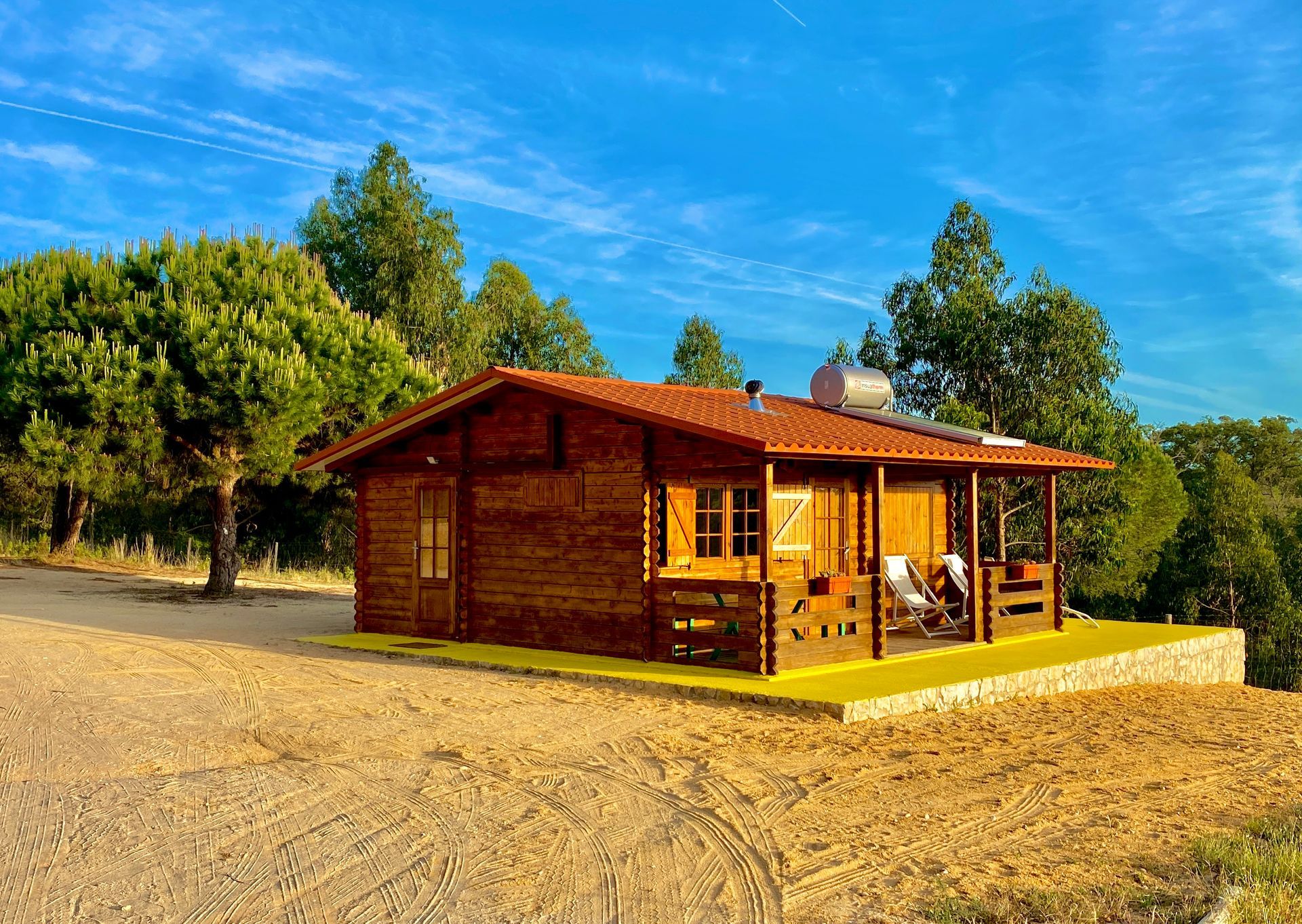 A small wooden house with a red roof is sitting on top of a dirt hill.