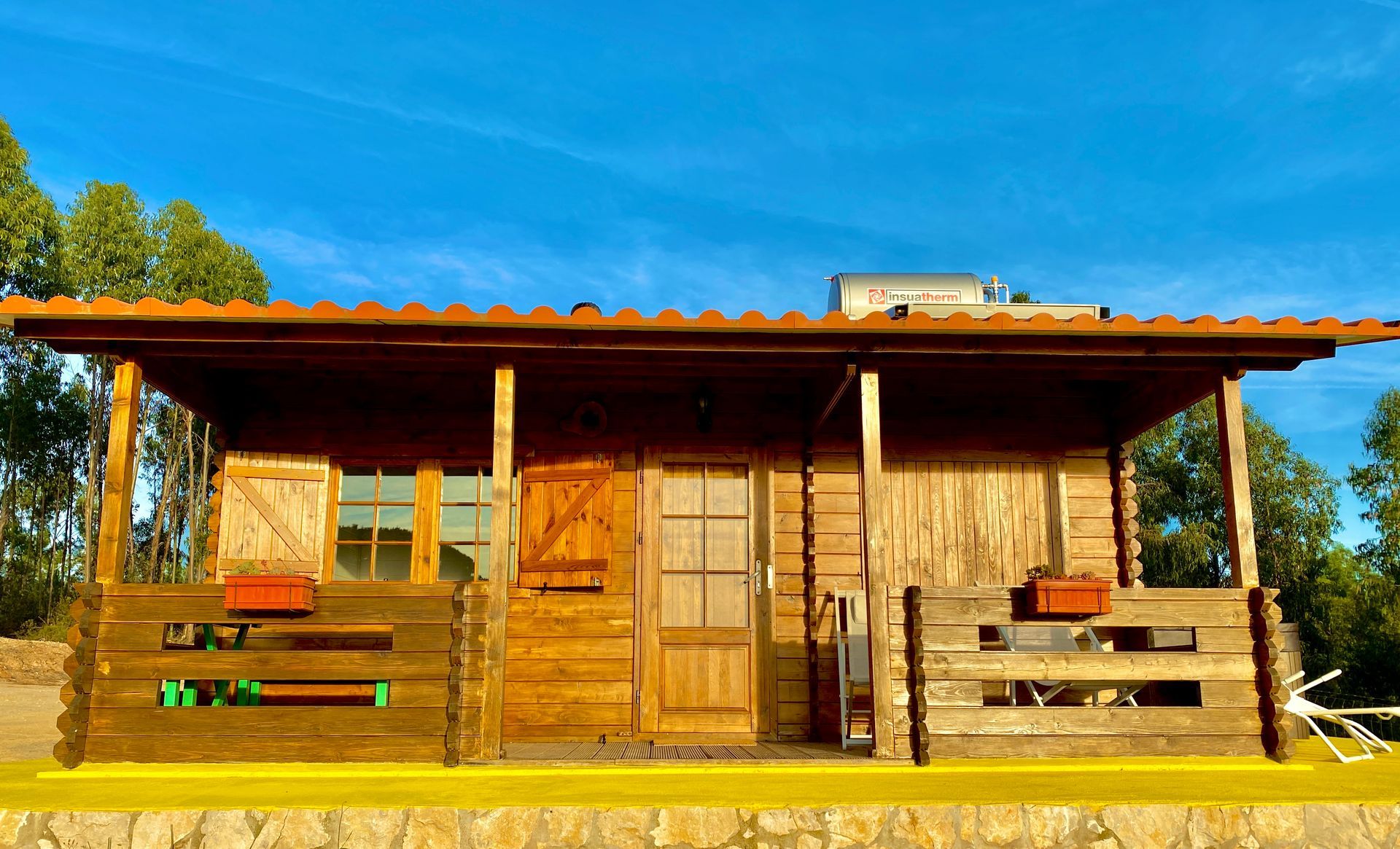 A small wooden house with a porch and a blue sky in the background.