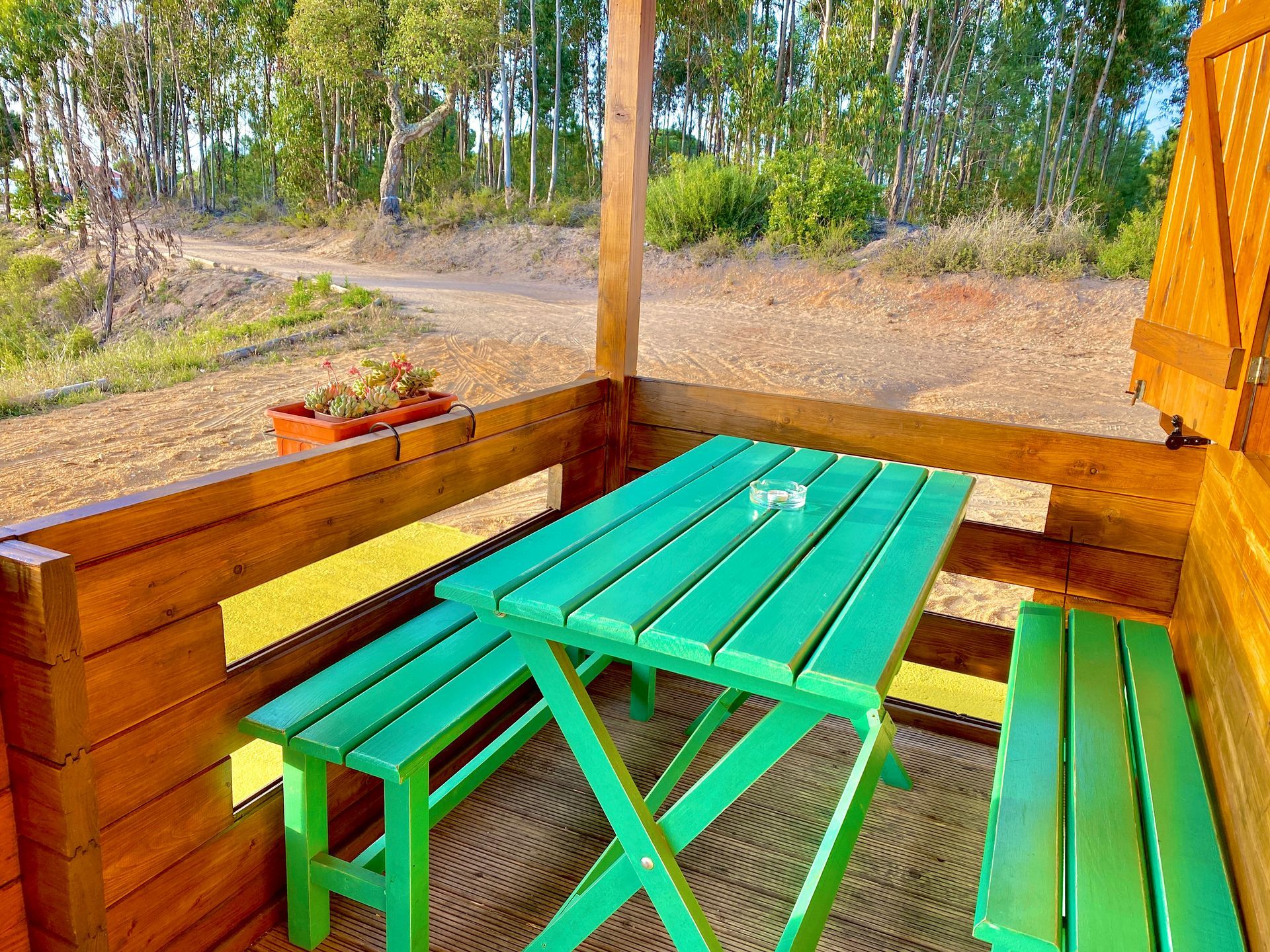 A wooden porch with a green picnic table and benches.