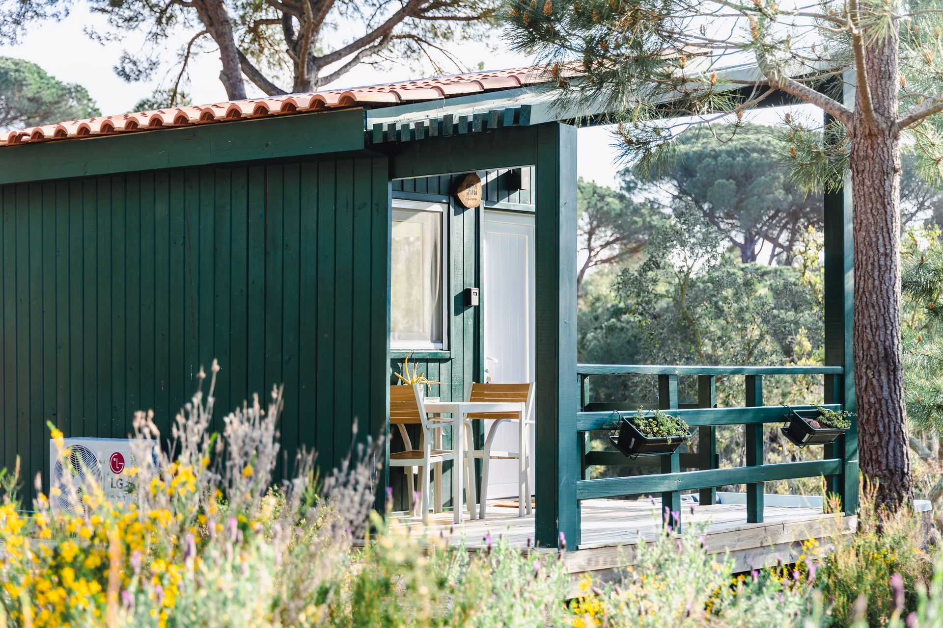 A small green house with a porch and a table and chairs on it.