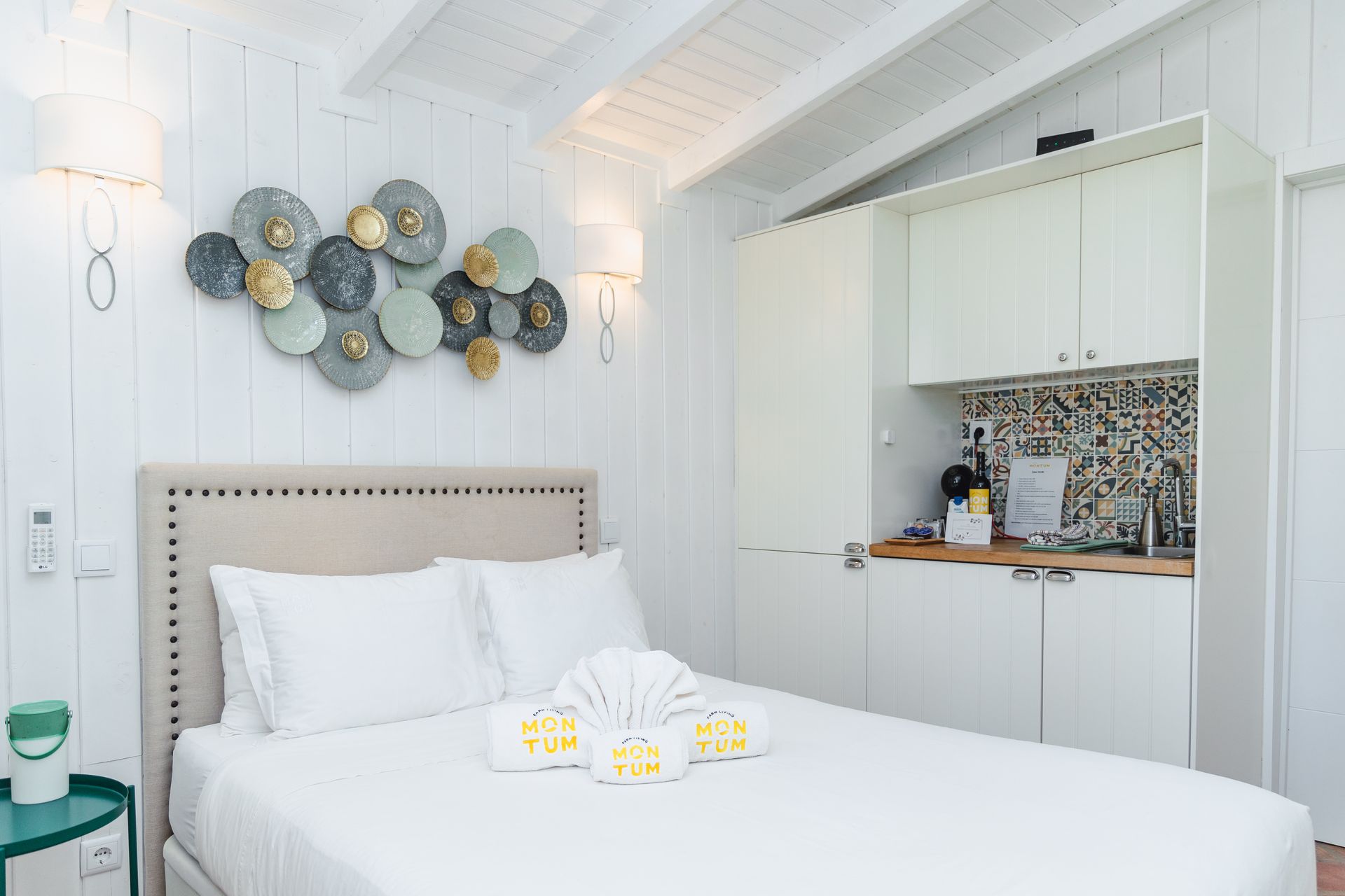 There is a bed in the middle of the room with a kitchen in the background.