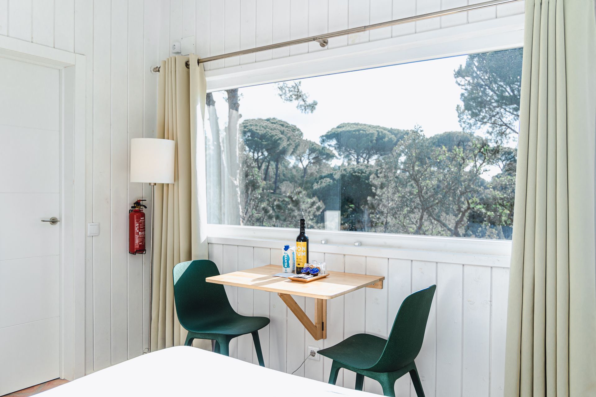 A bedroom with a table and chairs in front of a window.