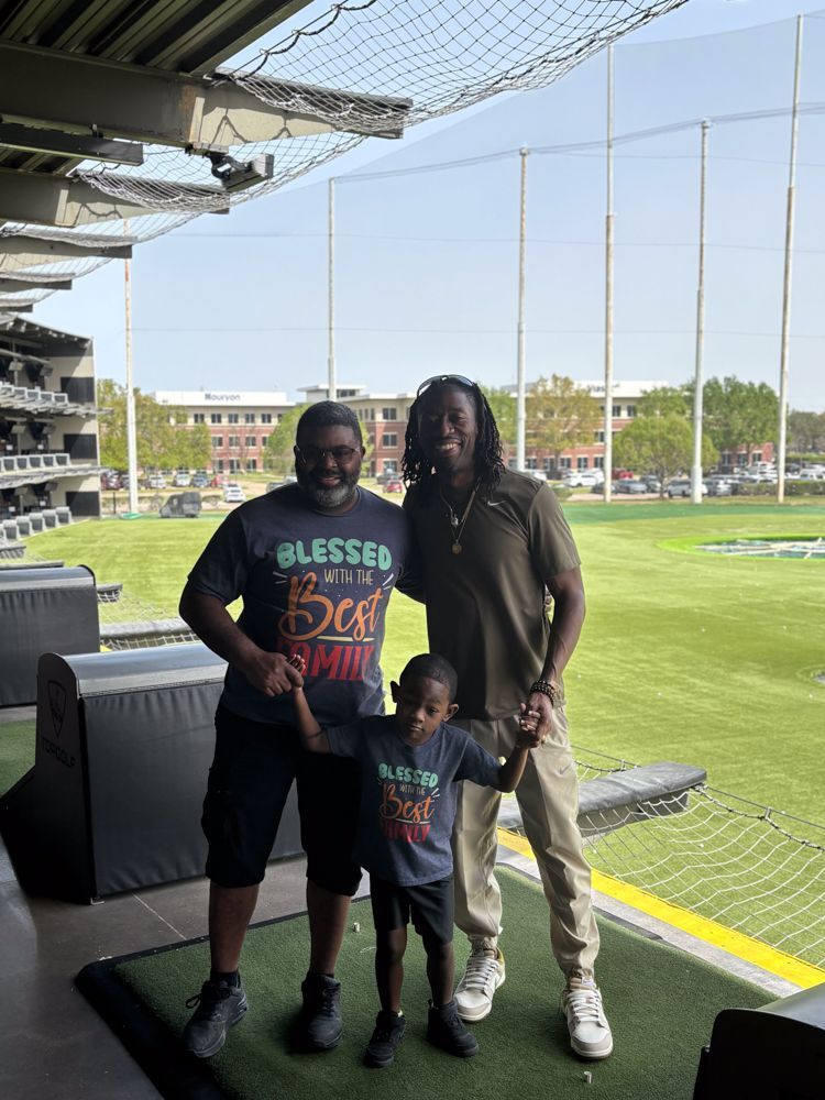 Two men and a child are posing for a picture on a golf course.
