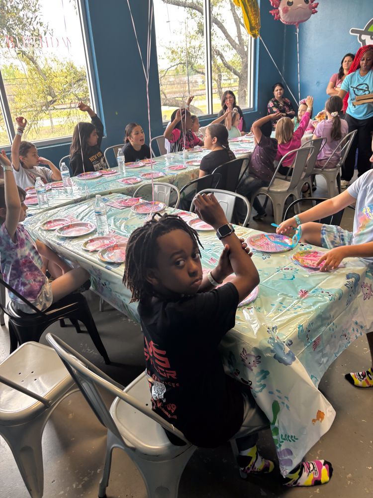 A group of children are sitting at tables at a birthday party.