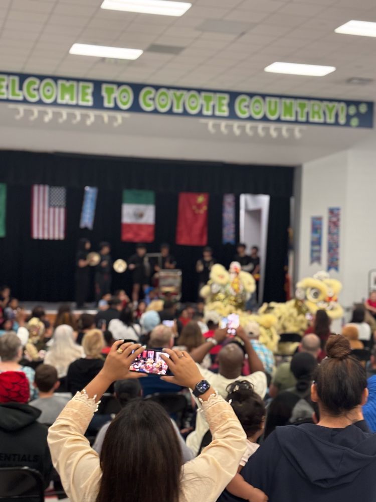 A woman is taking a picture of a group of people in front of a sign that says welcome to coyote country