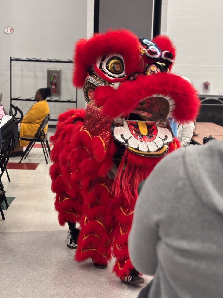 A group of people are watching a lion dance in a room