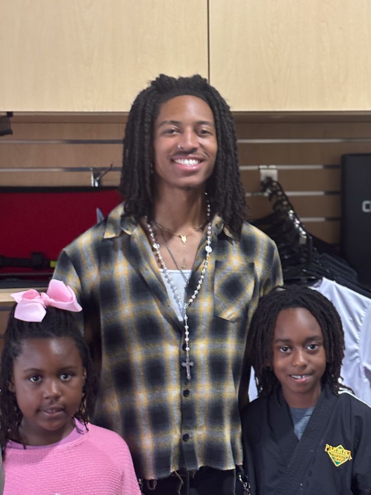 A man with dreadlocks is posing for a picture with two children