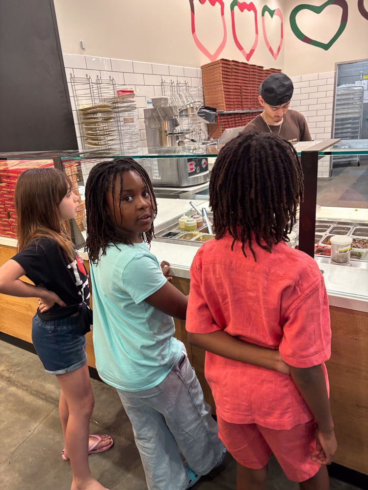 A group of children are standing in front of a counter in a restaurant.