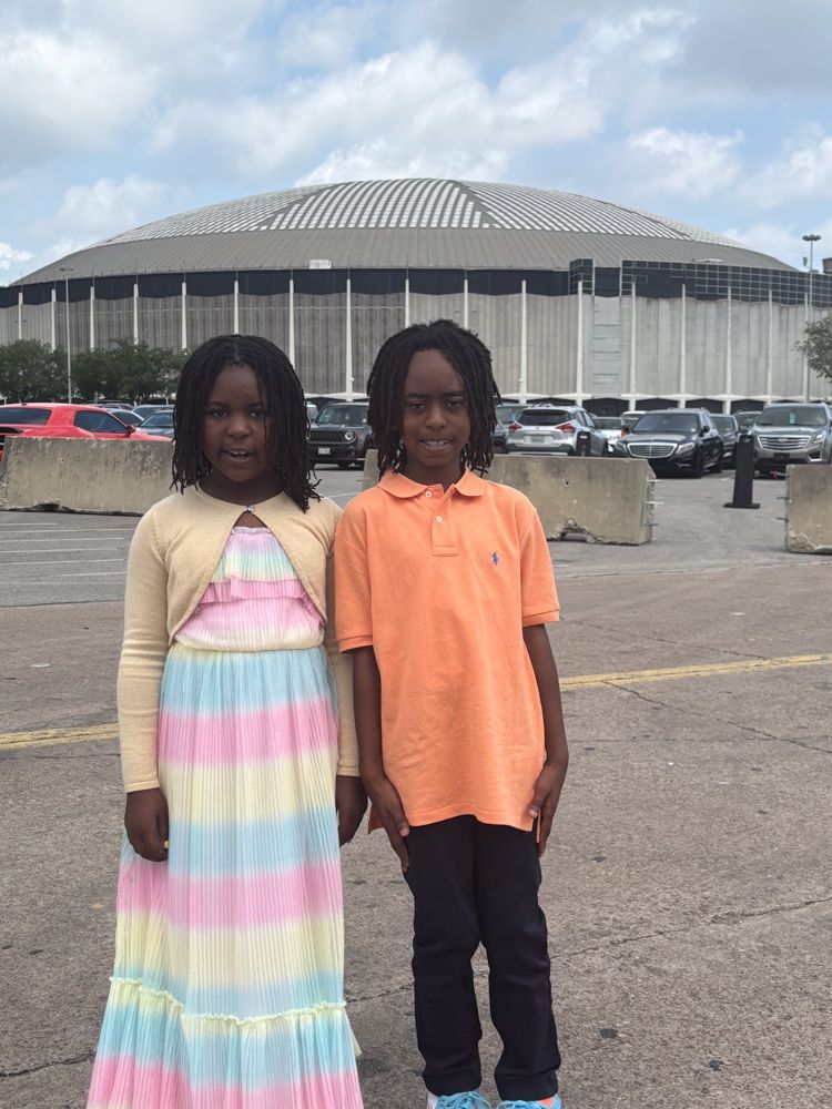 A boy and a girl are standing next to each other in front of a large building.