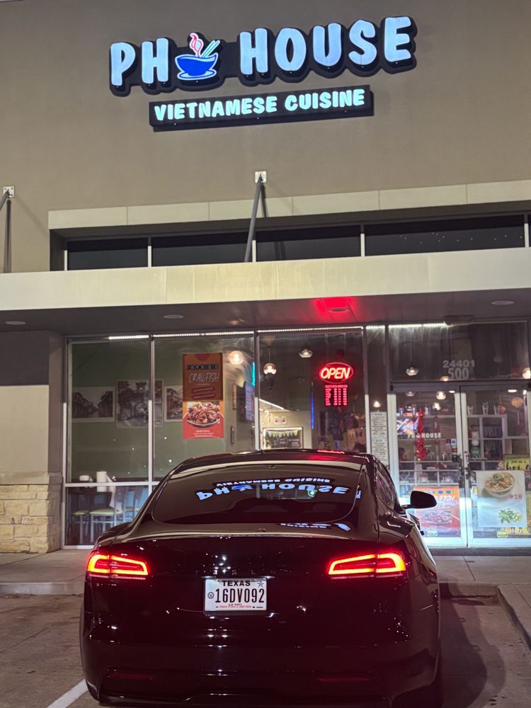 A car is parked in front of a phy house vietnamese cuisine restaurant