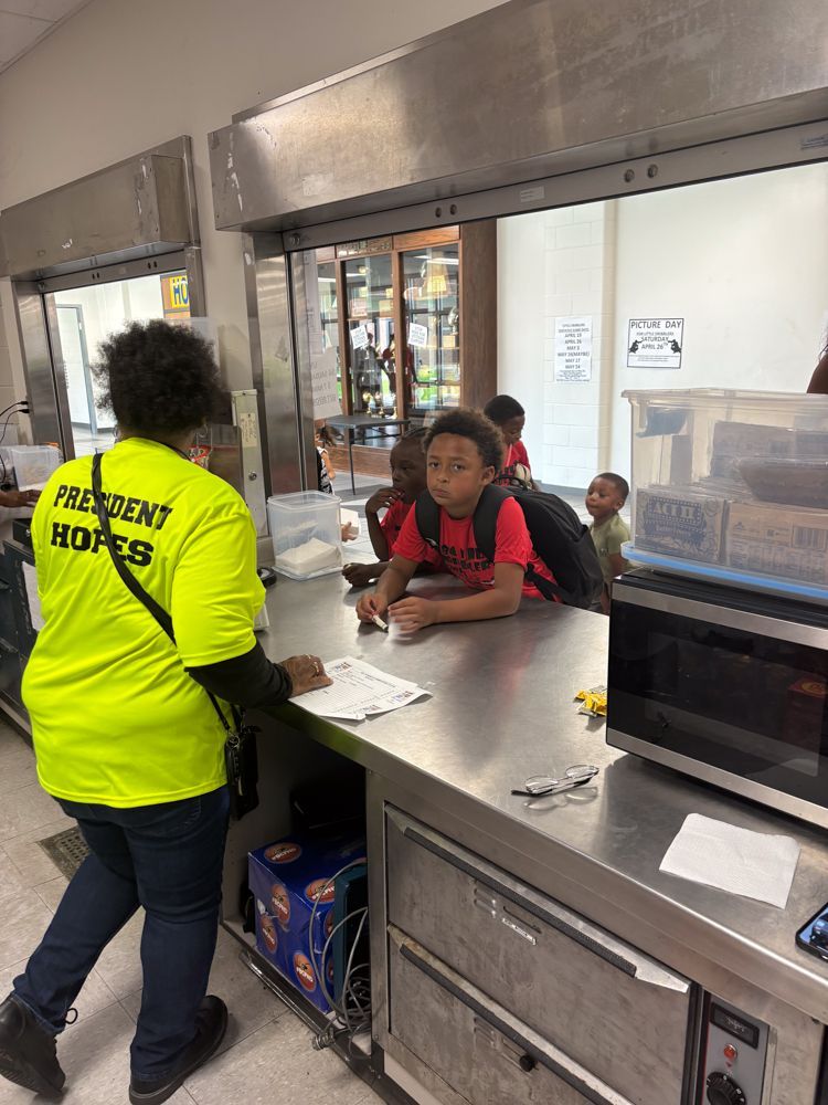 A woman in a yellow shirt is standing next to a boy in a red shirt.