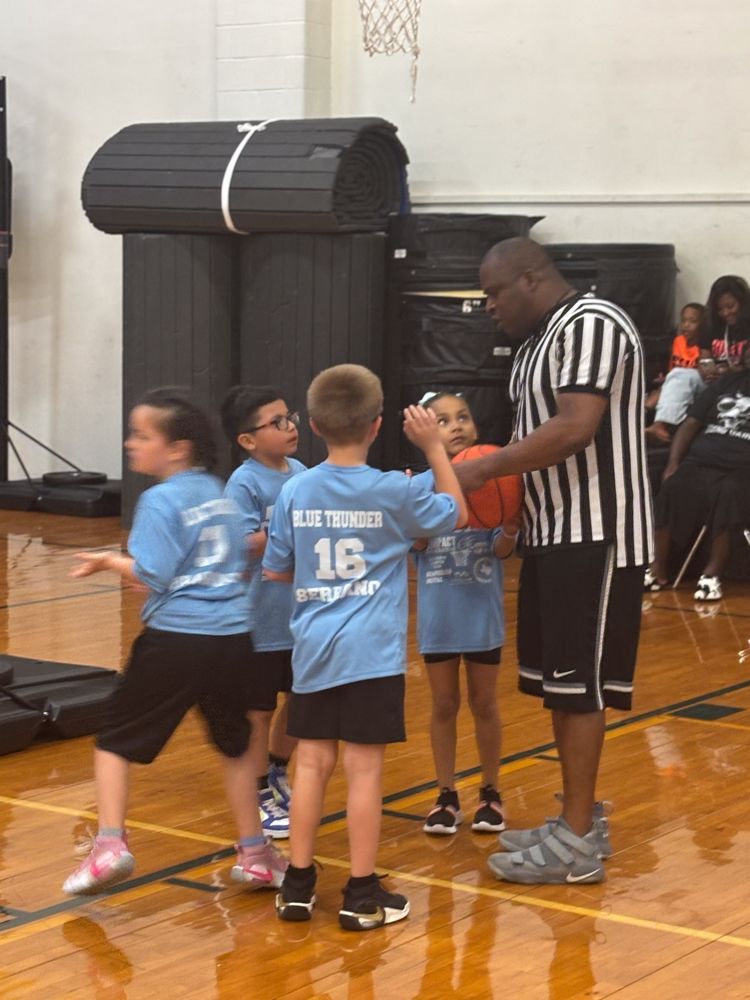 A referee talks to a group of young boys wearing blue shirts with the number 16 on them