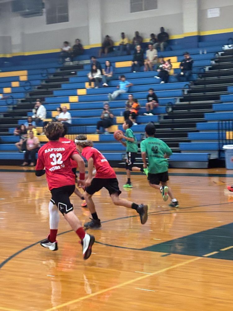 A group of young boys are playing basketball in a gym.