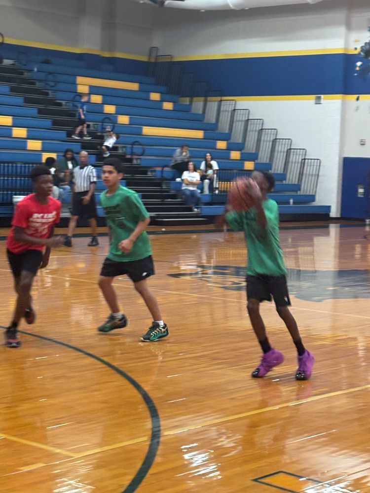 A group of young boys are playing basketball in a gym.