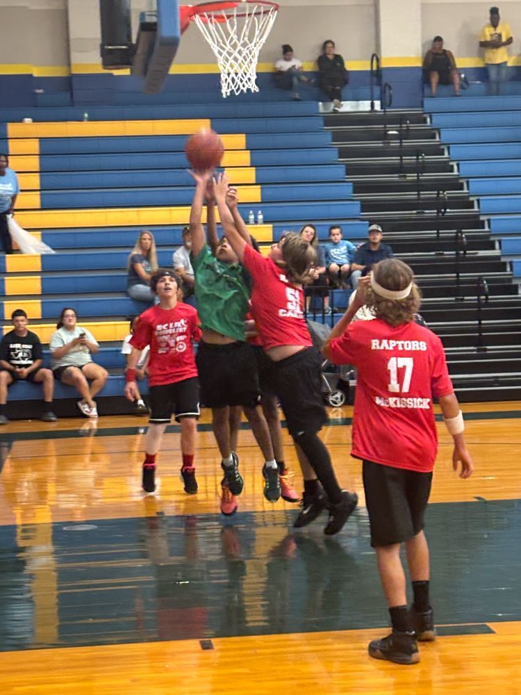 A group of young boys are playing basketball in a gym.