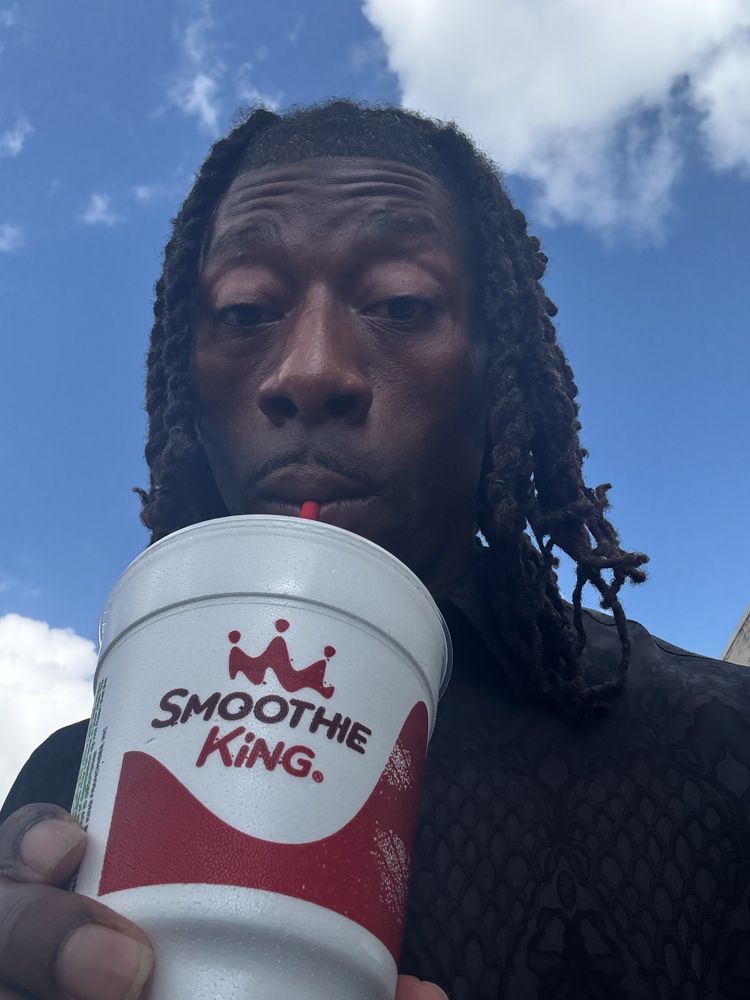 A man is drinking from a smoothie king cup