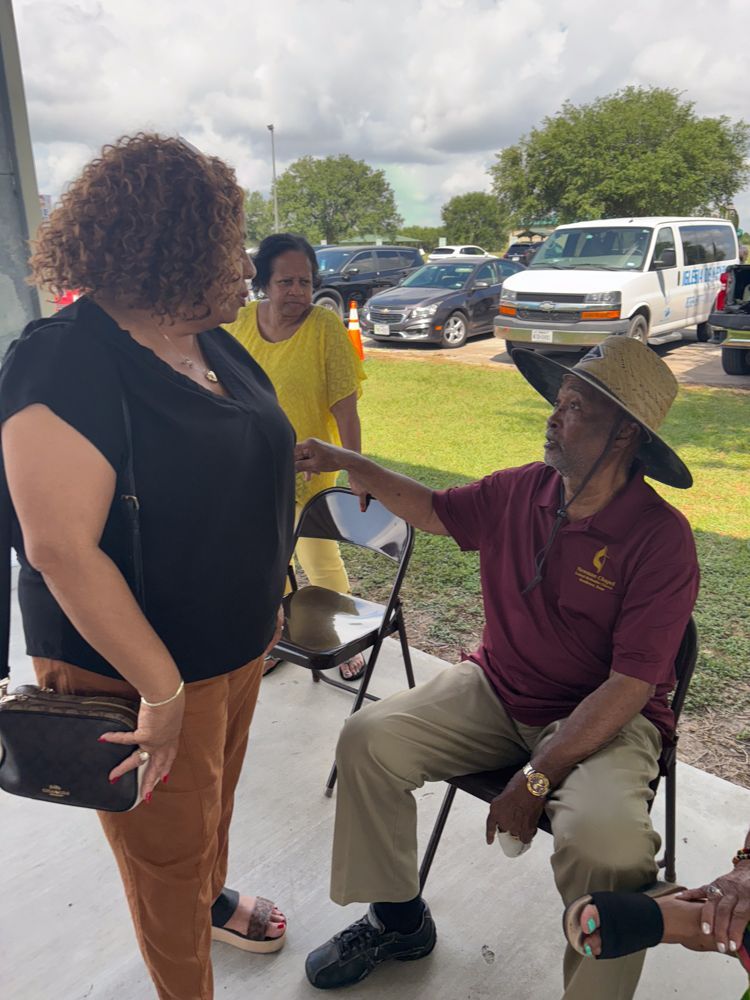 A man in a hat is talking to a woman in a black shirt