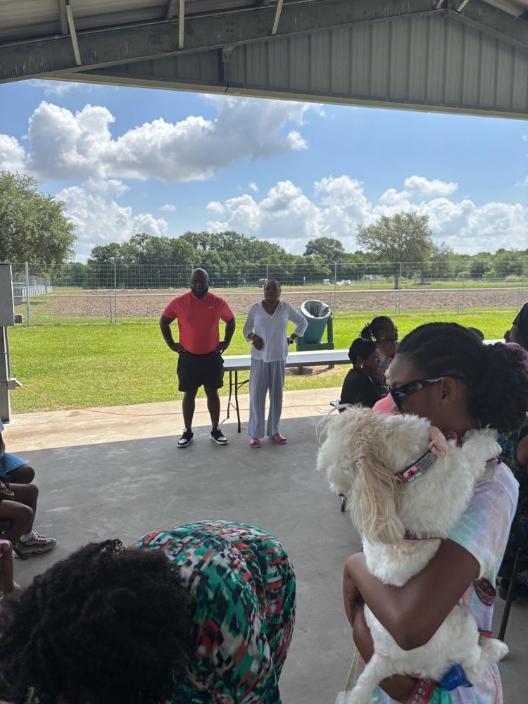 A woman is holding a small white dog in her arms.