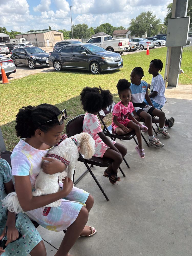 A woman is holding a dog while sitting in a chair with other children.