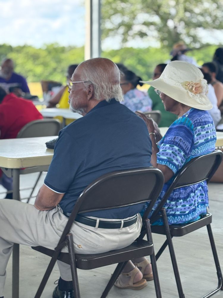 A man and a woman are sitting in folding chairs at a table.