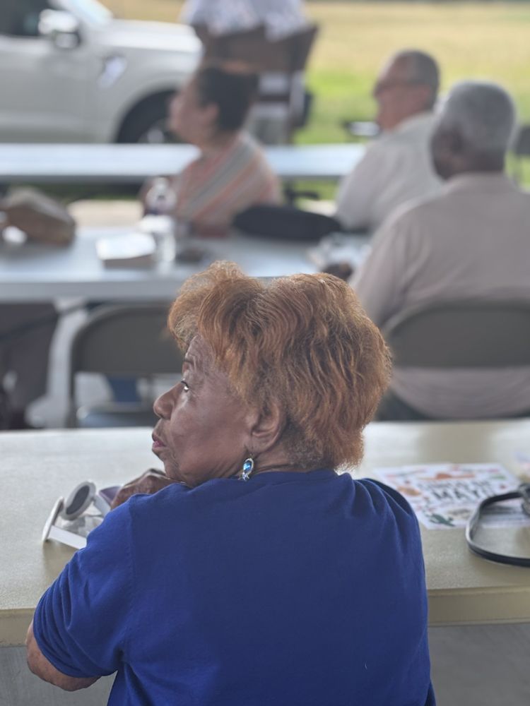A woman in a blue shirt is sitting at a table with other people.