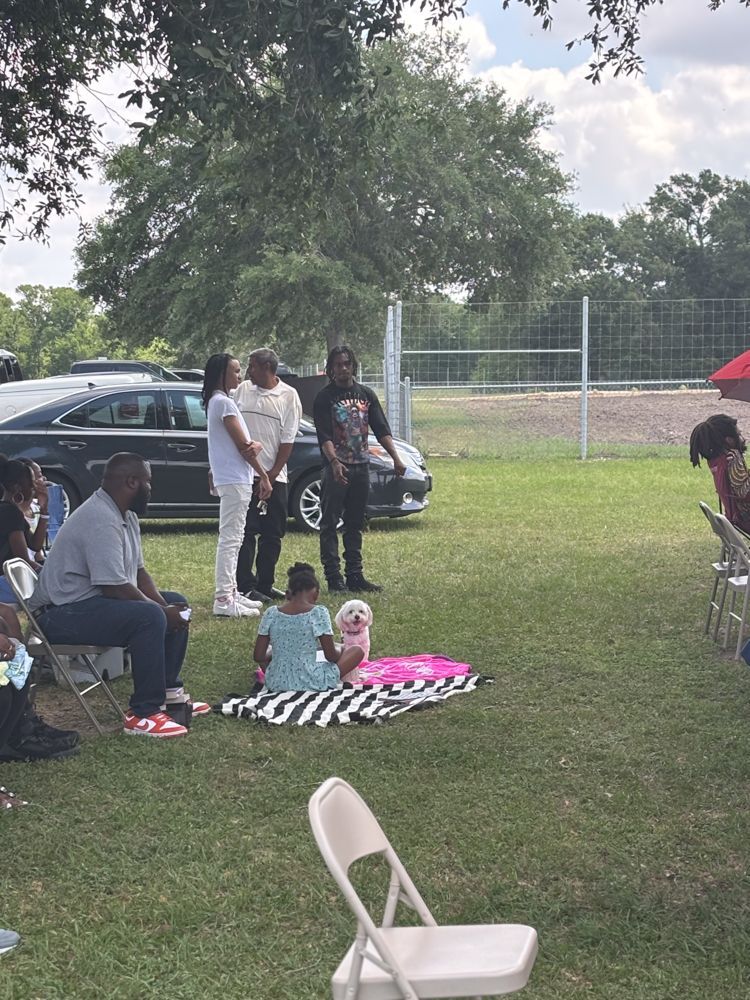 A group of people are sitting on the grass in a park.
