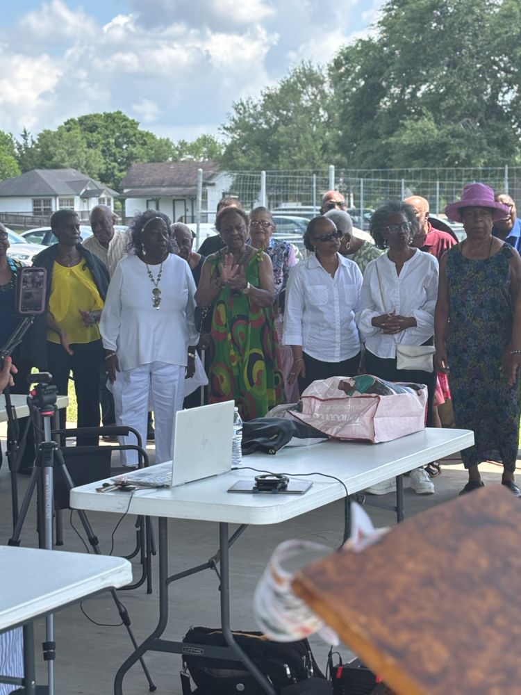 A group of people standing around a table with a laptop on it