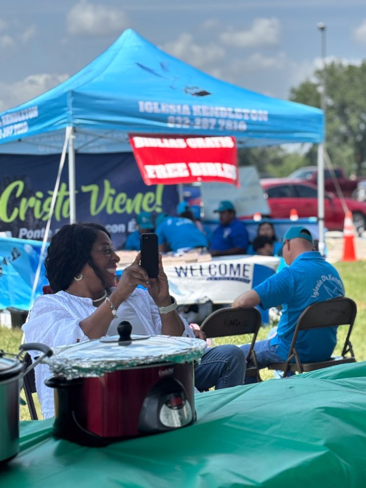 A group of people are sitting under a tent that says cristo viene