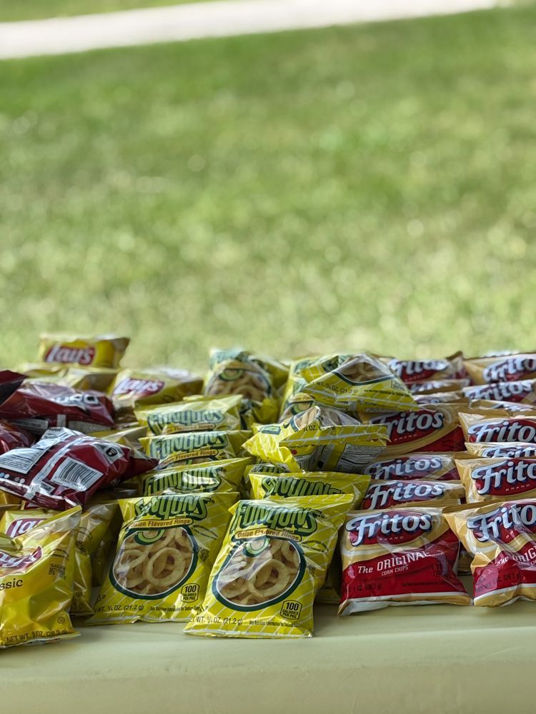 A table topped with bags of fritos and other snacks.