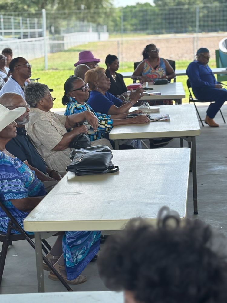 A group of people are sitting at tables outside.