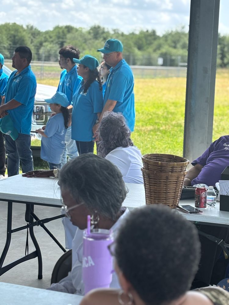 A group of people in blue shirts are standing around tables.
