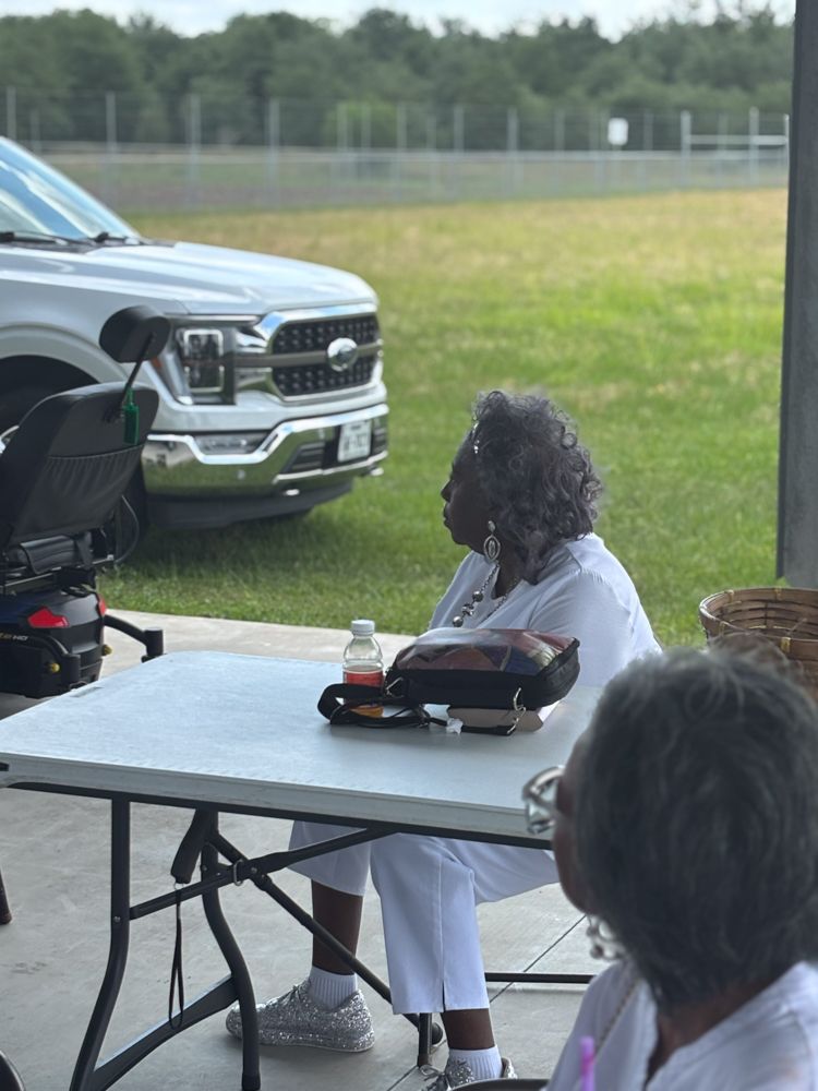 A woman is sitting at a table in front of a truck.