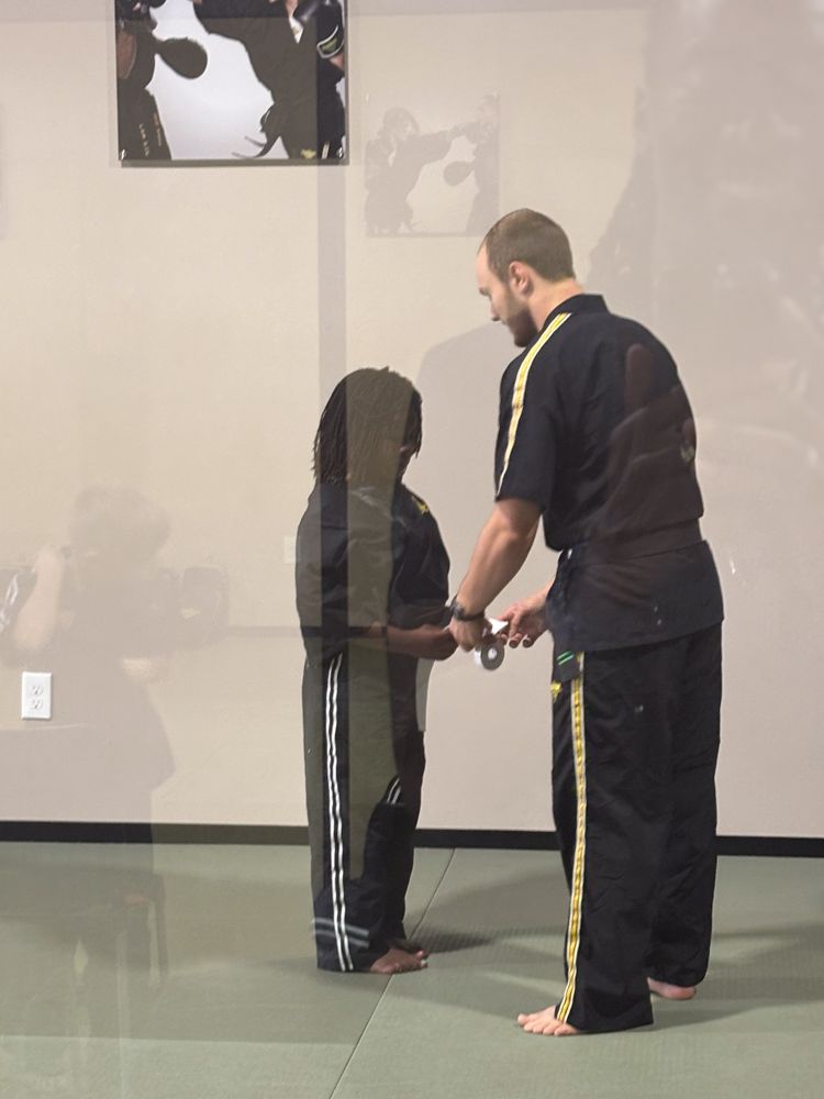 A man in a black shirt is standing next to another man in black pants