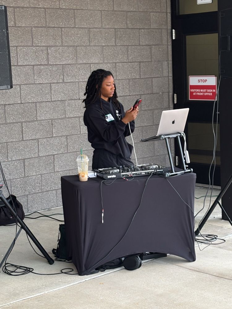 A woman is standing at a table with a laptop on it.