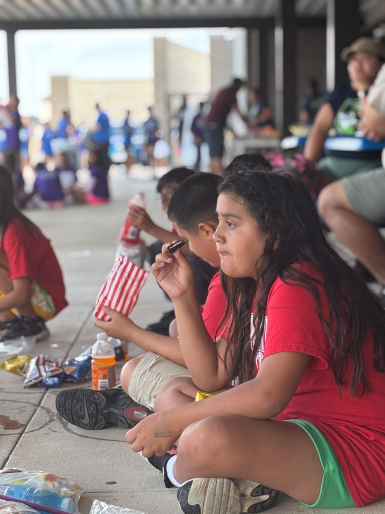 A group of children are sitting on the ground eating popcorn.