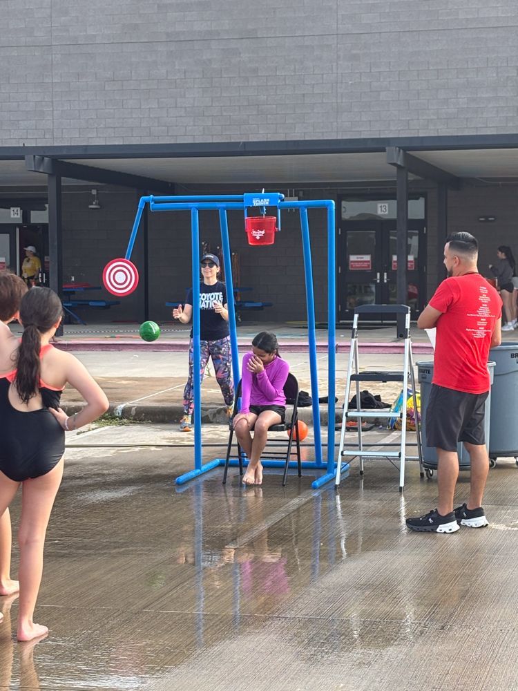 A man in a red shirt is standing in front of a swing set.